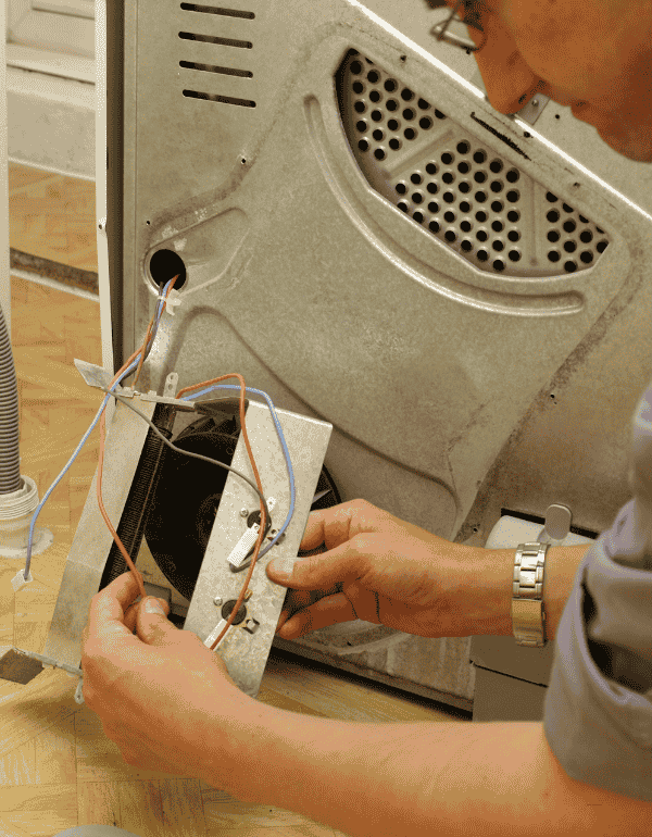 Technician repairing a dryer, focusing on wiring and internal components, highlighting professional appliance repair services in Toronto.