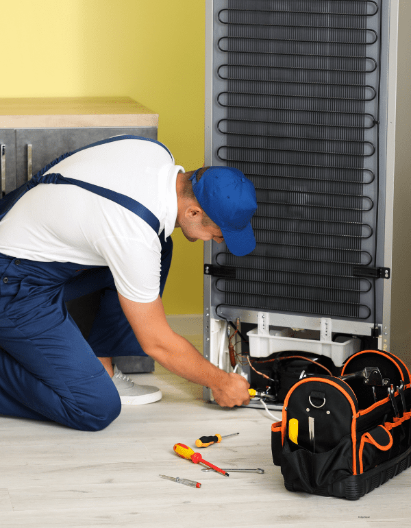 Technician repairing a freezer, surrounded by tools, showcasing expertise in appliance repair services offered by Toronto Appliance Repair.