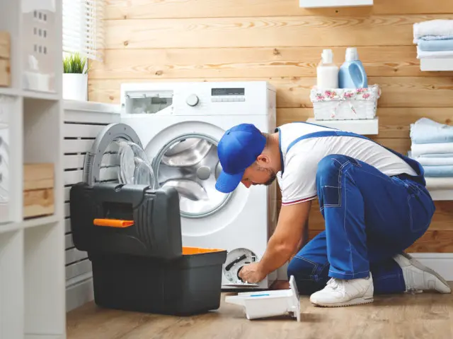 Certified technician repairing a commercial dryer, equipped with tools, in a clean laundry room setting, emphasizing expertise in appliance repair services.