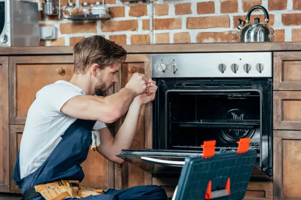 Technician repairing a Haier oven, showcasing professional appliance service in a kitchen setting.
