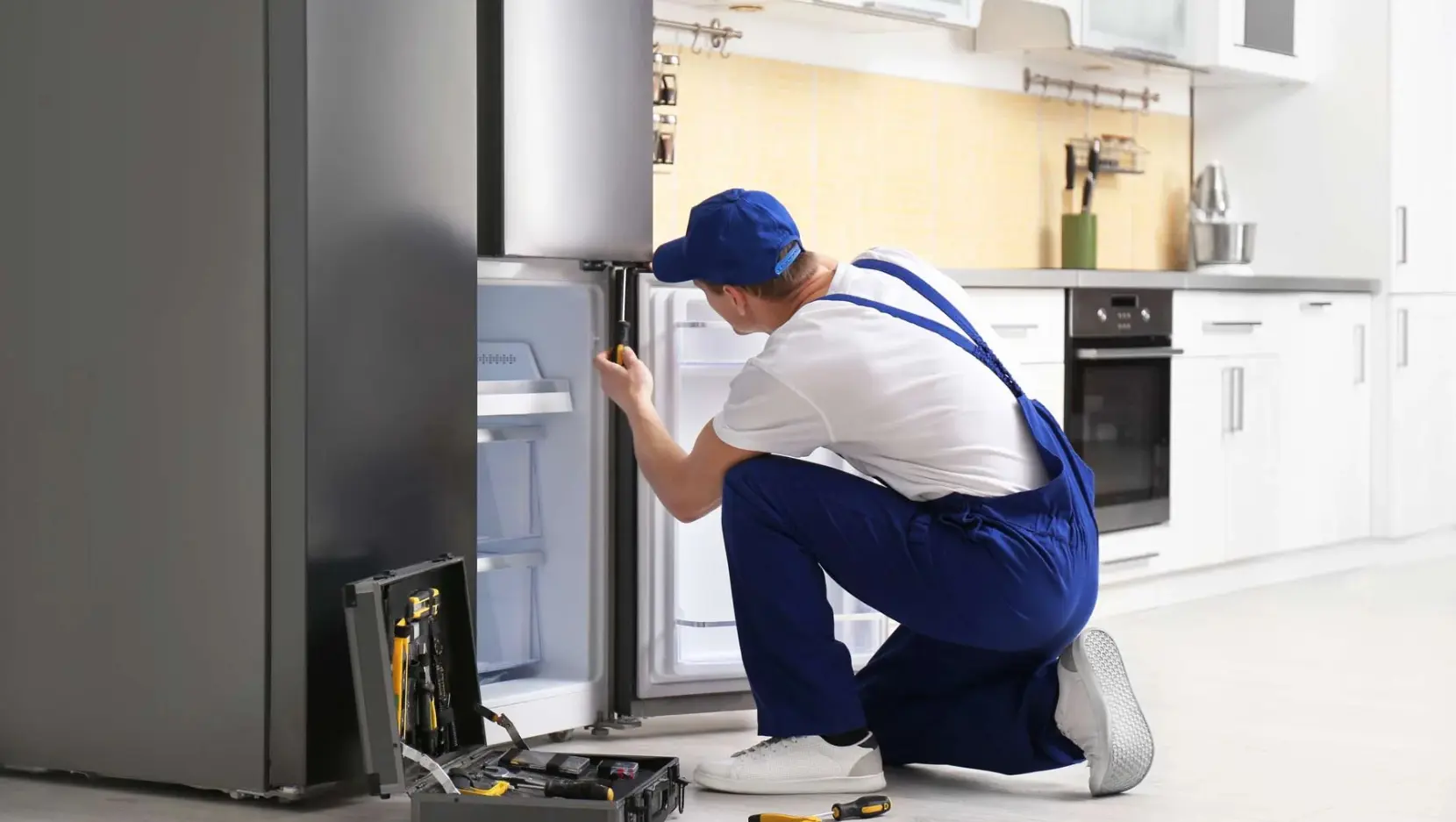 Appliance Expert technician repairing refrigerator, preventive maintenance tips for home appliances.