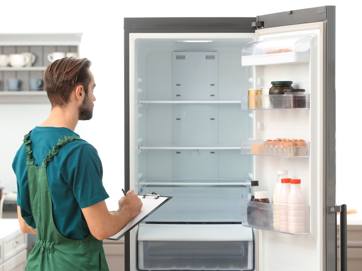 Technician inspecting empty refrigerator during appliance repair assessment in Toronto.